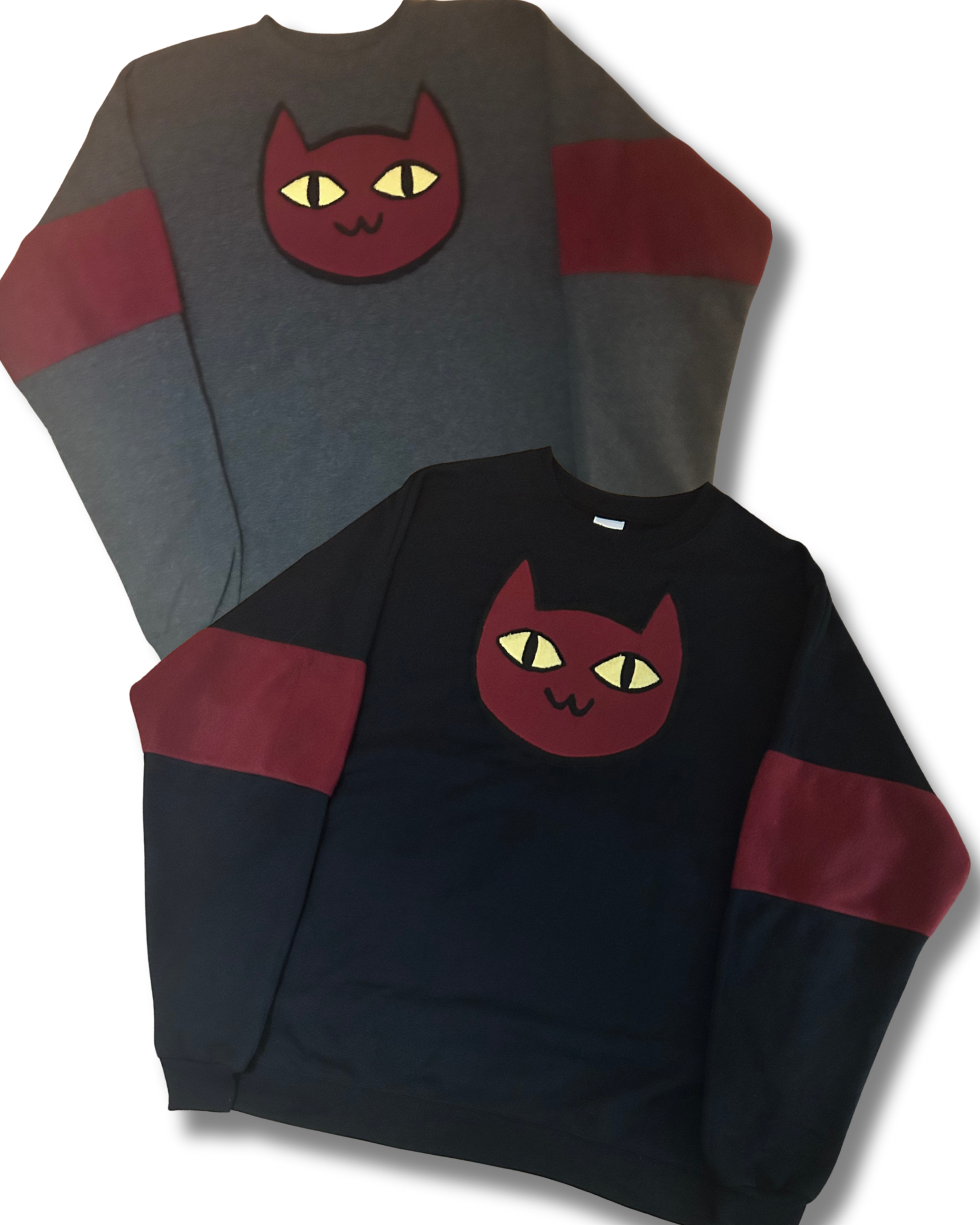 Two sweatshirts, one gray and one black, with a red and yellow cat face design on a white background.