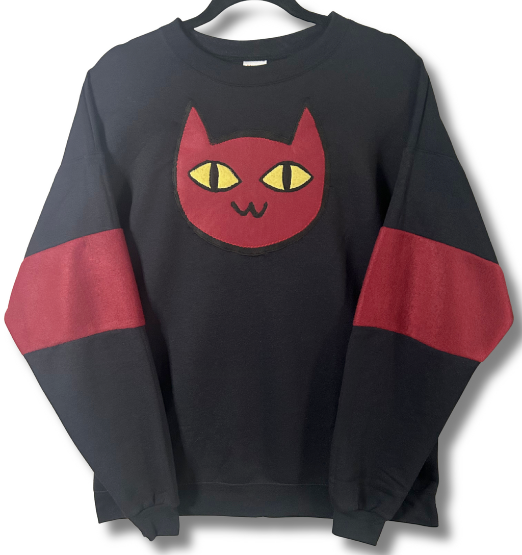 Black sweatshirt with a red cat face design on a white background